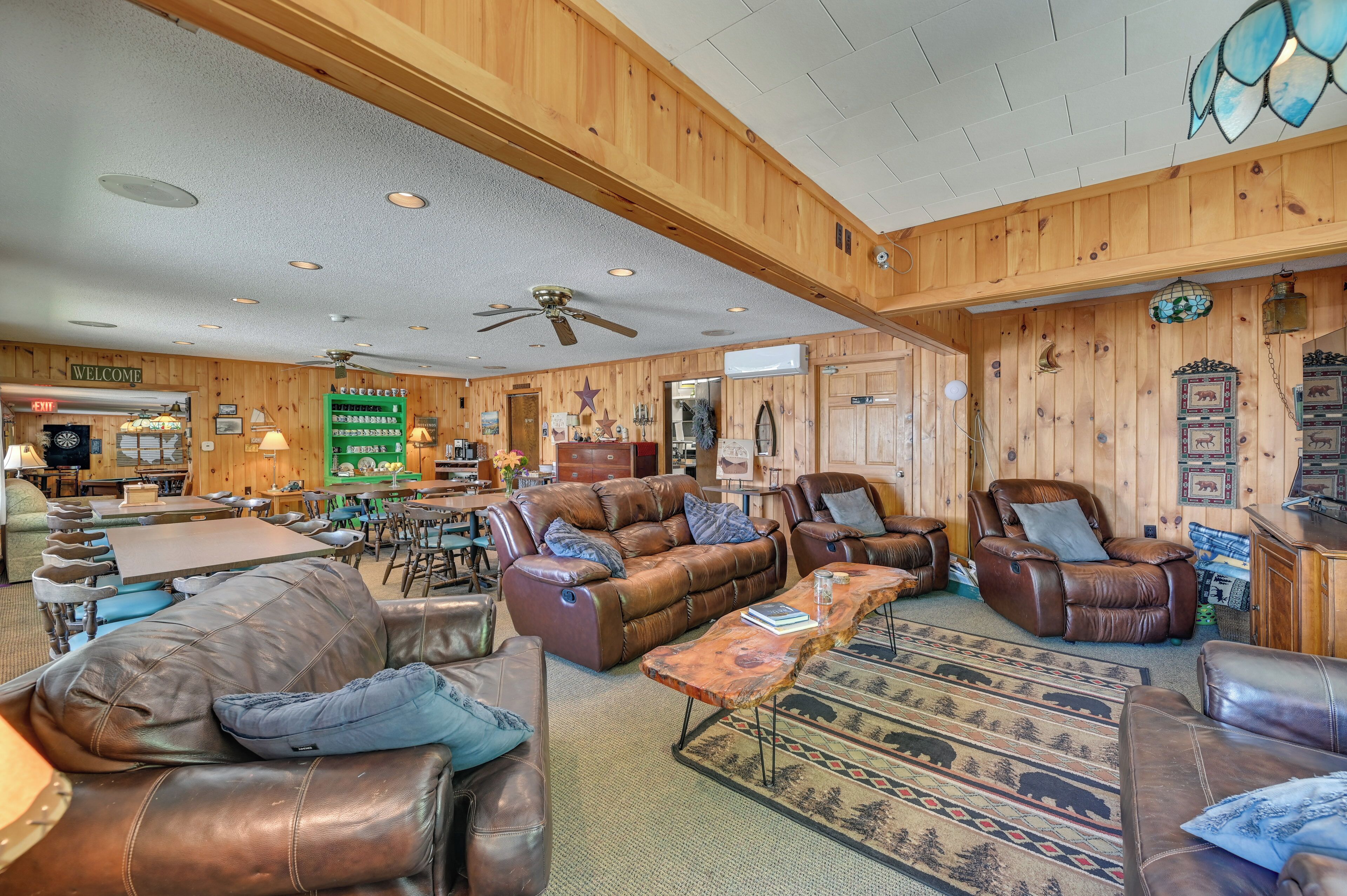 A spacious room with leather sofas, a dining area, and a ceiling fan.