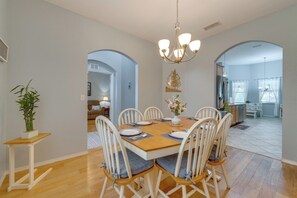 A dining area with a wooden table, white chairs, and a chandelier.