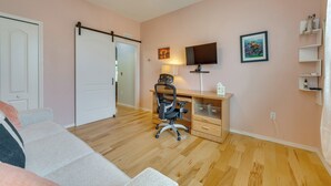 Um quarto com uma cama, uma escrivaninha com cadeira, uma televisão e uma porta.