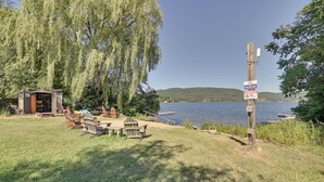 A lakeside picnic area with a small shelter, wooden chairs, and tables. - Gather Lakeside at Willsboro Inn on Lake Champlain (Willsboro)