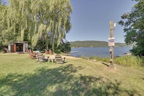 A lakeside picnic area with a small shelter, wooden chairs, and tables. - Gather Lakeside at Willsboro Inn on Lake Champlain (Willsboro)