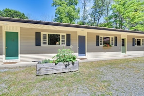 A row of single-story cabins with individual doors and windows, a gravel driveway, and a wooden planter with greenery in the foreground. - Gather Lakeside at Willsboro Inn on Lake Champlain (Willsboro)
