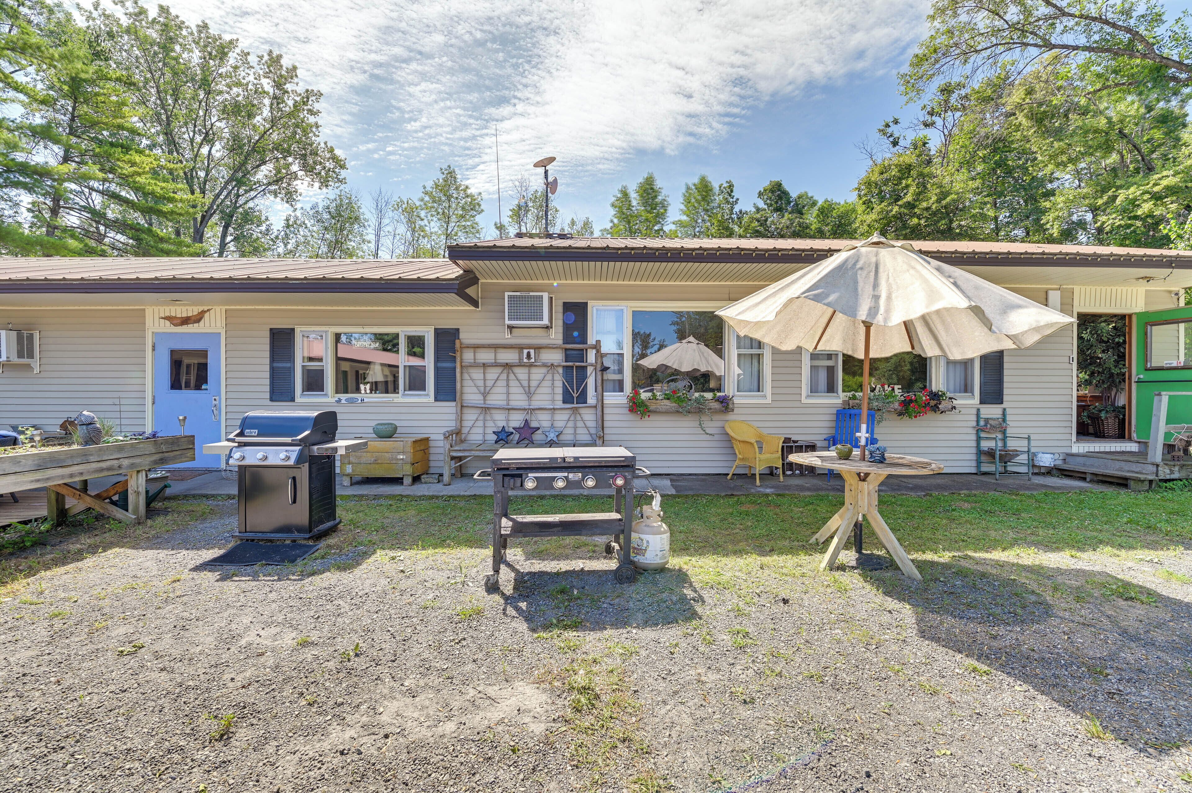 A two-story building with a patio area, outdoor grill, and a covered seating area.