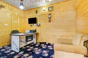 A reception area with a reception desk, a clock, a television, and a bed with a floral bedspread. - Collection O Brein Nishat (Srinagar)