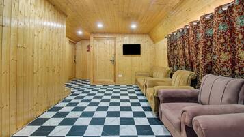Quarto com paredes de madeira, chão quadriculado, televisão e sofá.