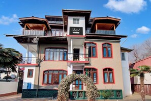A multi-story building with a central staircase, balconies, and a sign indicating a company-serviced establishment. - Collection O Brein Nishat (Srinagar)