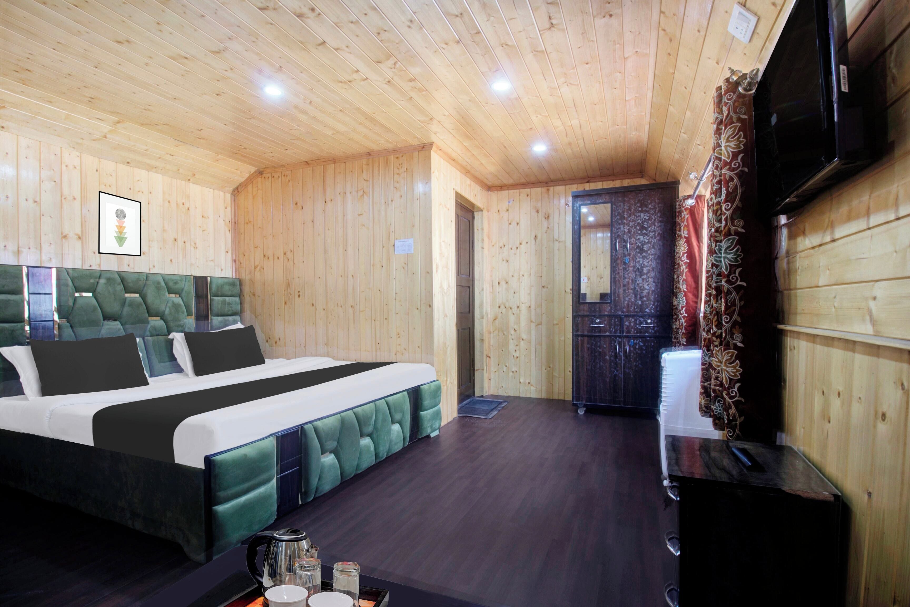 Una habitación con paneles de madera, una cama, un televisor y una puerta que da a otra habitación.