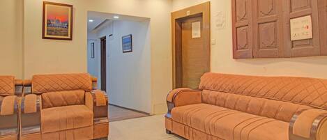 A reception area with a wooden door, a wall-mounted light switch, and a framed picture on the wall.