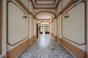 A corridor with patterned flooring, arched ceilings, and wall-mounted lighting fixtures. - Casalina 2 (Naples)