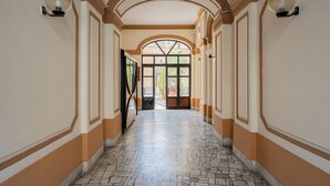 Un corridoio con pavimento piastrellato, soffitto a volta e una porta che dà all'esterno.