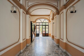 Ein Korridor mit Fliesenboden, gewölbter Decke und einer zur Außenseite führenden Tür.