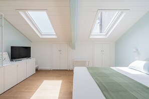 A bedroom with a bed, a TV, a desk, and a wardrobe. There are skylights on the ceiling. - Casalina 2 (Naples)