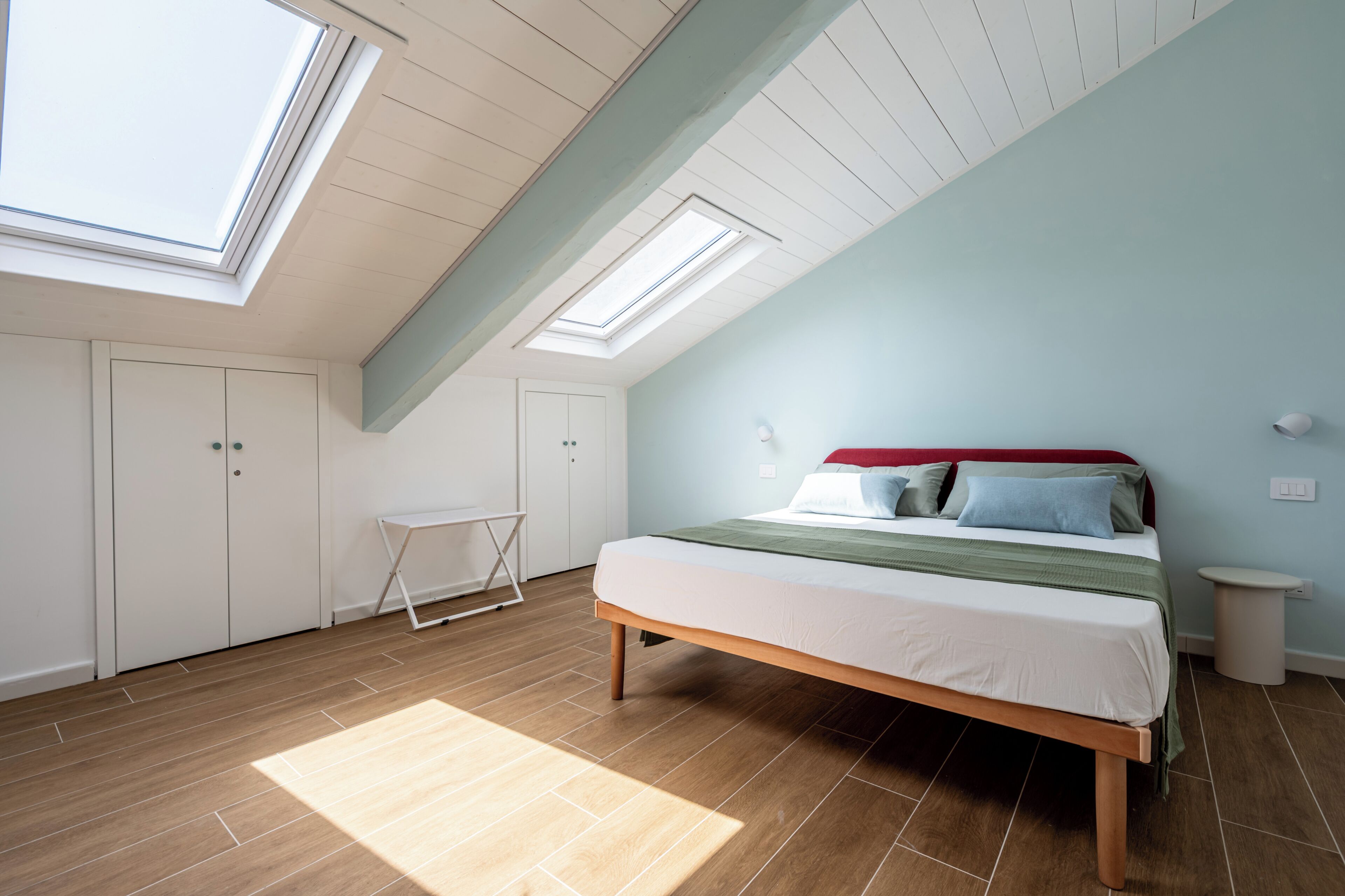 Une chambre à coucher avec un puits de lumière, un lit, une table de chevet et une armoire.