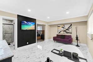 Ein modernes Wohnzimmer mit Marmorboden, einem Flachbildfernseher, einem violetten Sofa und einem Gemälde an der Wand.