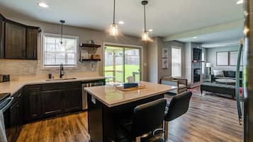 A modern kitchen with dark wood cabinets, a large island with bar stools, and pendant lighting.