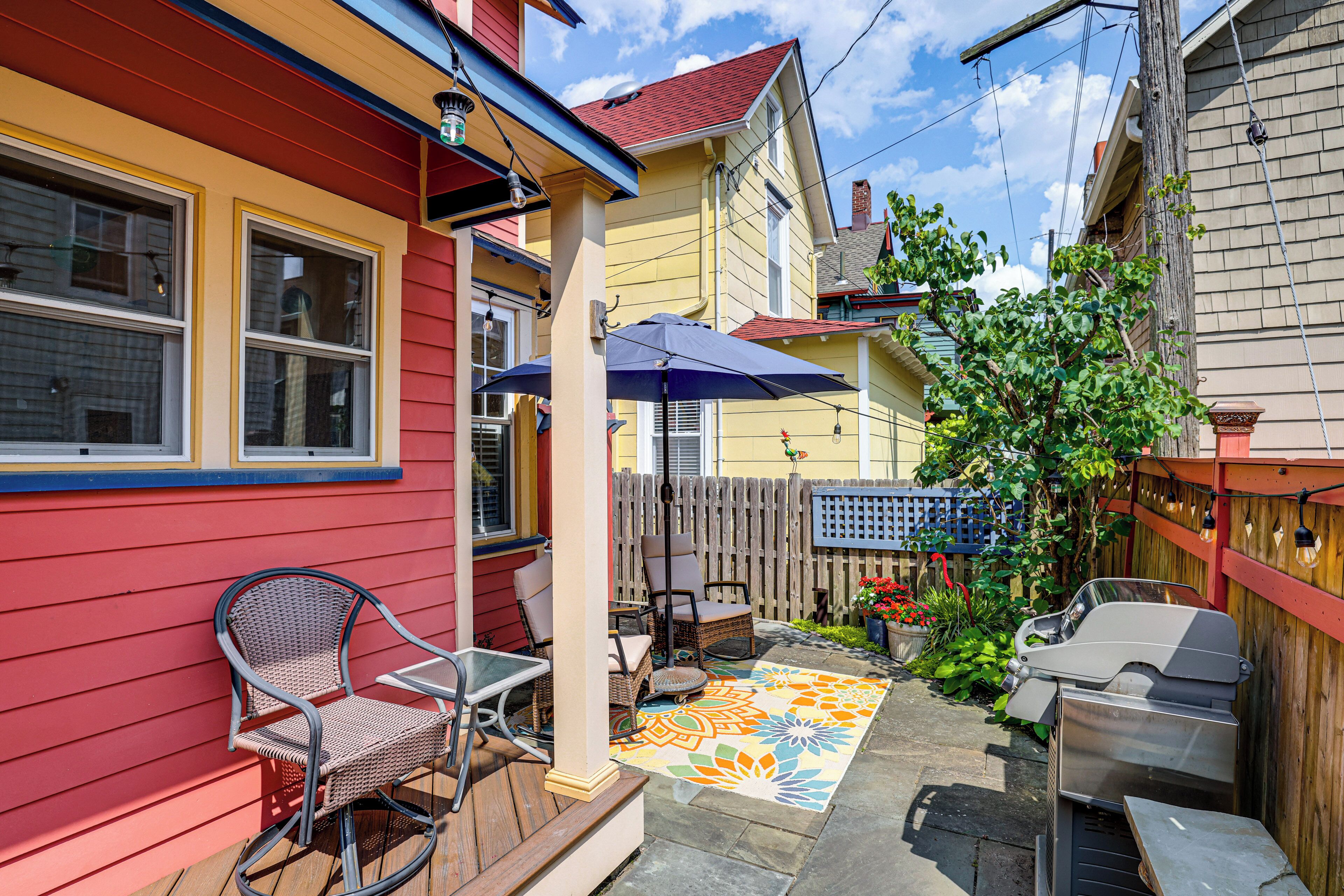 Une terrasse avec des meubles d’extérieur, un tapis coloré et un barbecue.