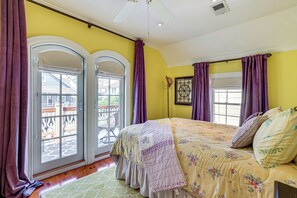 A bedroom with a bed, two windows with purple curtains, and a view of the outside. - Walkable Victorian Cottage in Historic Ocean Grove (Ocean Grove)