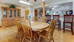 A dining area with a wooden table and chairs, a ceiling fan, and a cabinet with glass doors. - Grill & Fenced Yard! Longmont Home, Walk to Parks (Longmont)