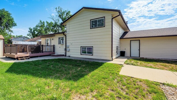 A residential building with a front deck, a small porch, and a grassy yard. - Grill & Fenced Yard! Longmont Home, Walk to Parks (Longmont)