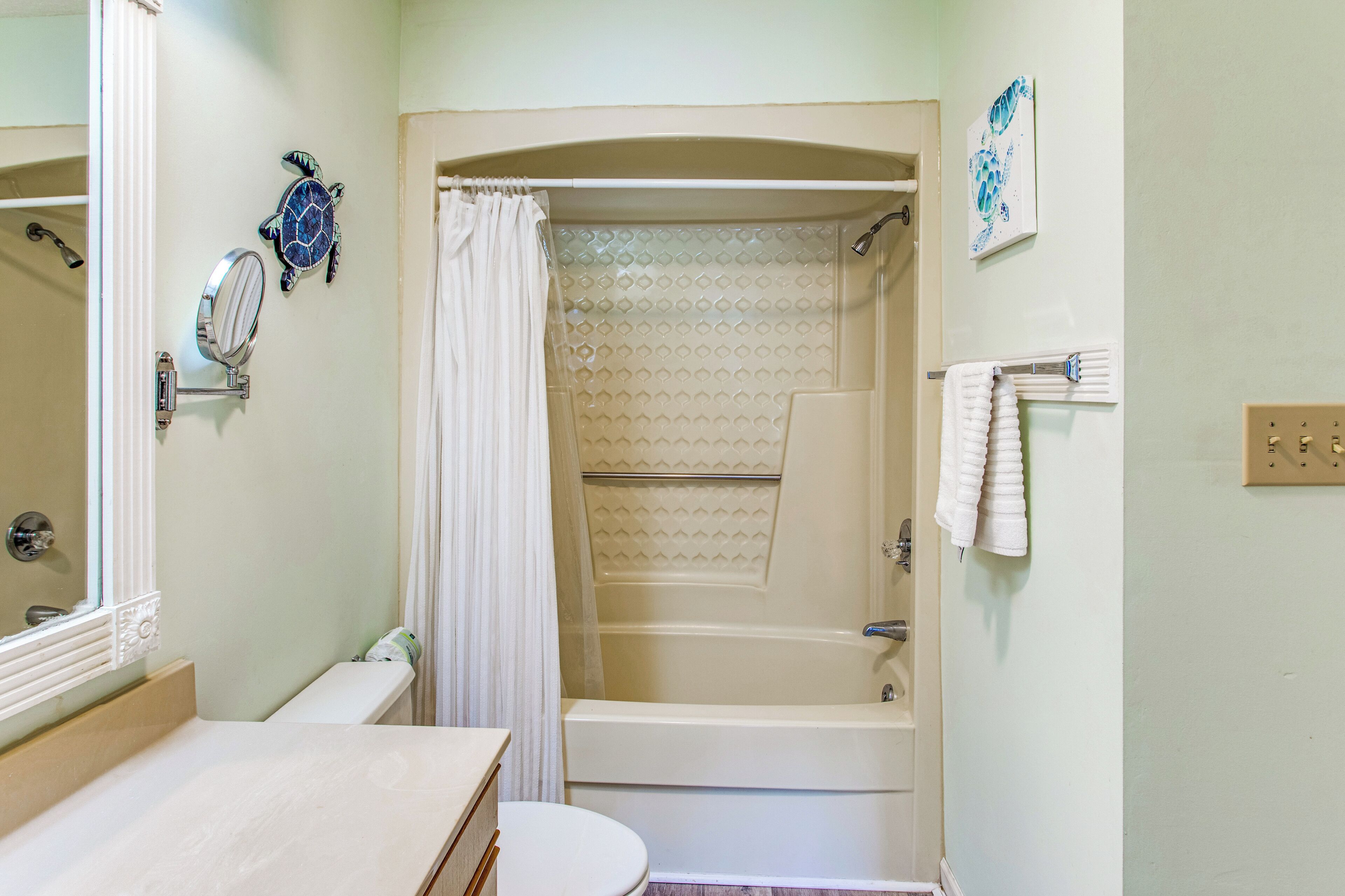 Ein Badezimmer mit Badewanne, Toilette, Waschbecken, Spiegel und Duschvorhang.