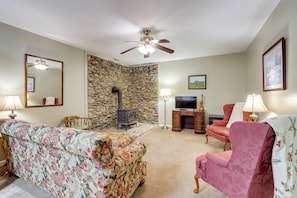 A living room with a stone wall, a fireplace, a television, and floral-patterned furniture.