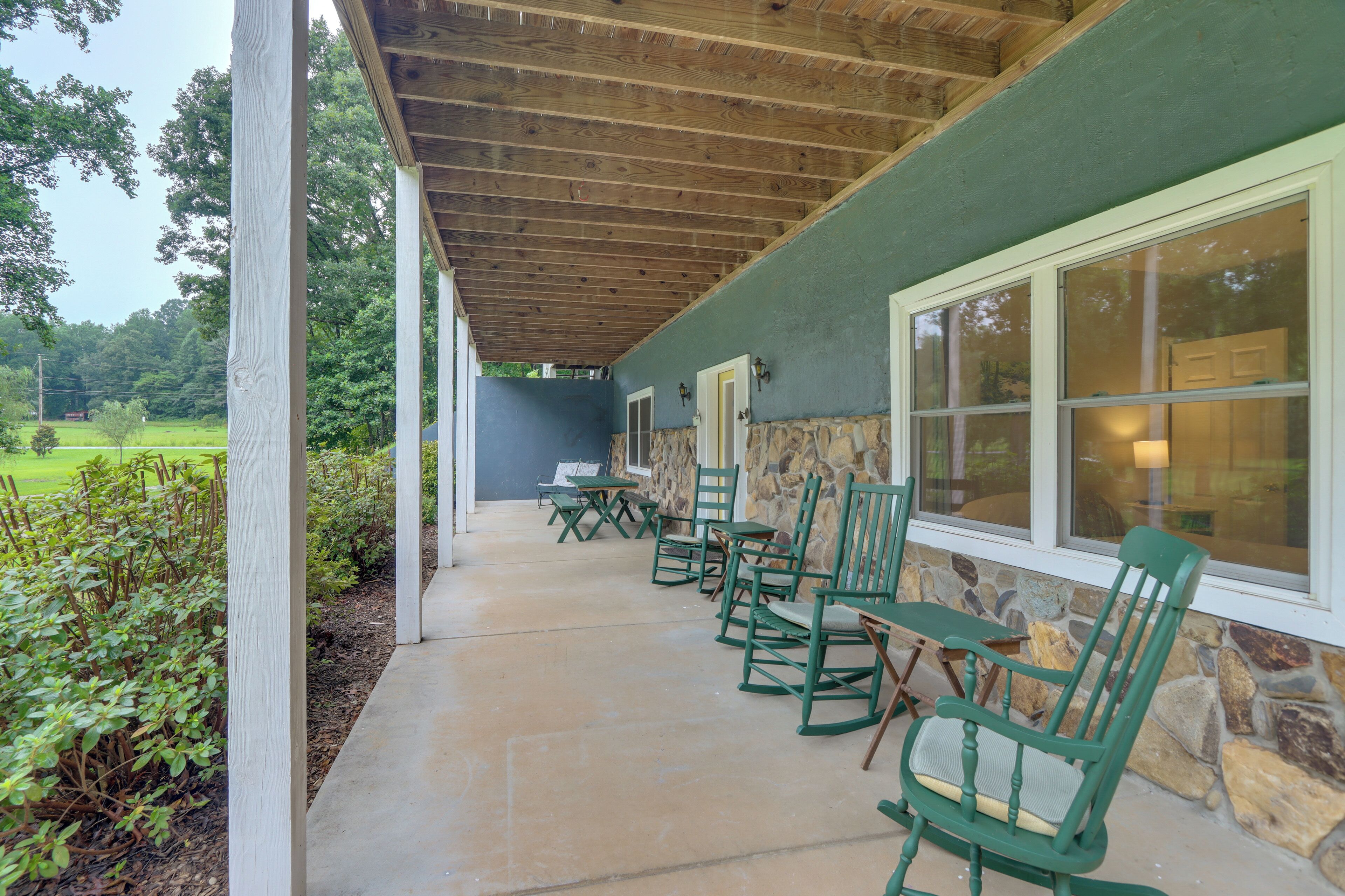 Ein überdachter Patio-Bereich mit Sitzgelegenheiten und Blick auf eine grüne Landschaft.