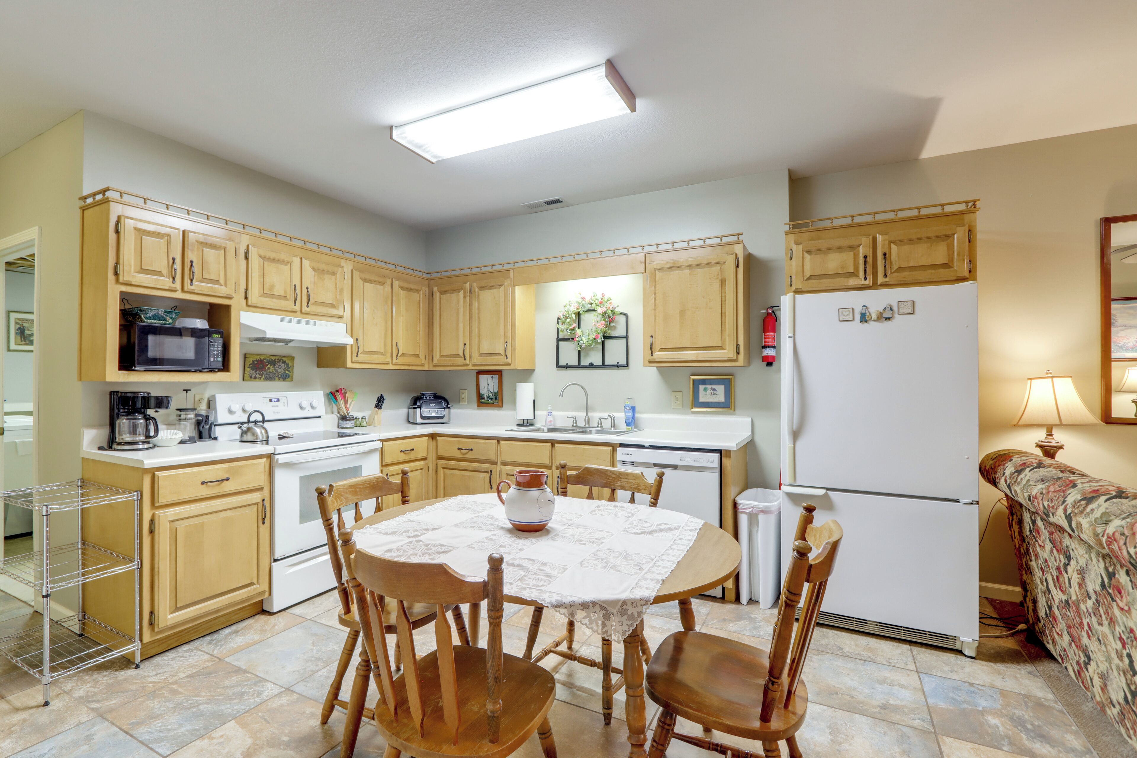 A kitchen with wooden cabinets, a dining table with chairs, a refrigerator, and a microwave.