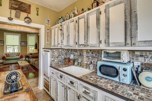 A kitchen with a vintage aesthetic, featuring a white sink, a blue microwave, and a toaster.