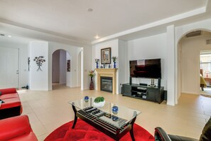 A spacious living room with a fireplace, a flat-screen TV, and a red sofa. - Vegas Extended Retreat w/ Furnished Patio (Las Vegas)