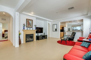 Una sala de estar moderna con chimenea, televisor y sofá rojo.