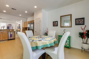 A dining area with a table set for four, white chairs, a green side table, and a potted plant. - Vegas Extended Retreat w/ Furnished Patio (Las Vegas)