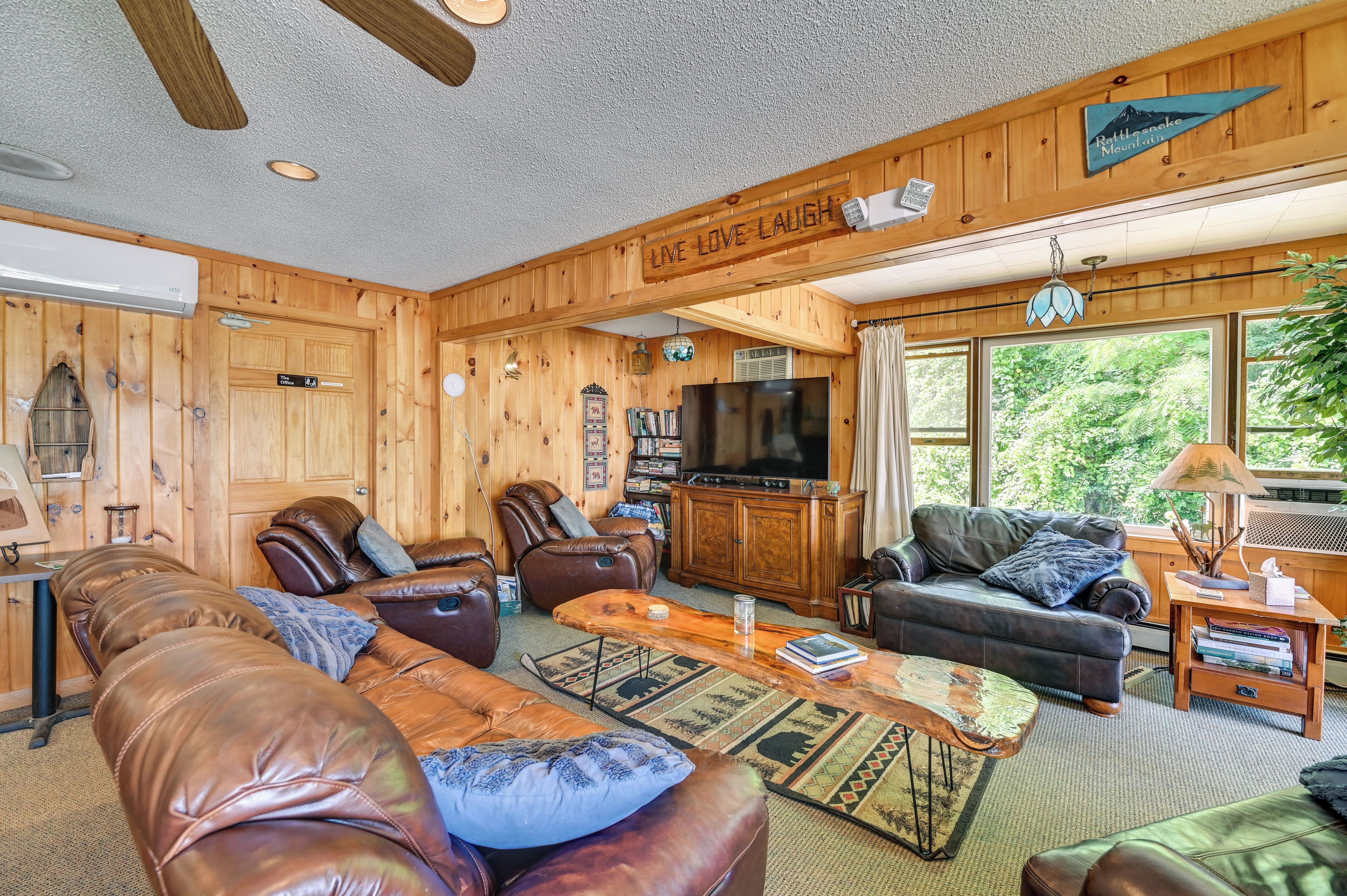 A wooden-paneled living room with leather sofas, a coffee table, and a television.