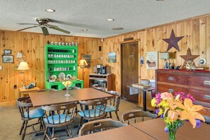 A cozy room with a wooden interior, a green shelf with mugs, a table with chairs, and a ceiling fan. - Lake Champlain Waterside Retreat w/ Dock Access (Willsboro)