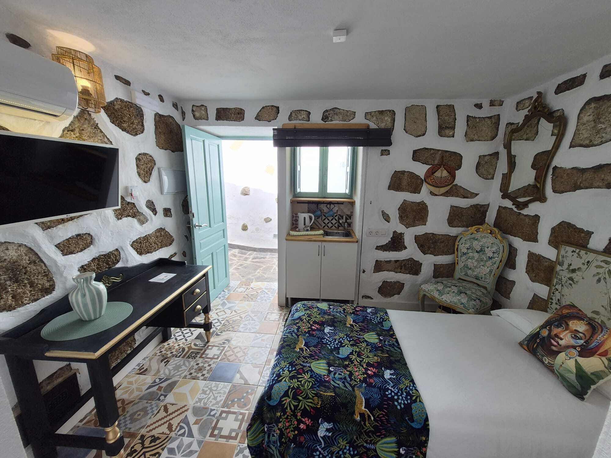 Een kamer met een bed, een bureau, een stoel en een raam.
