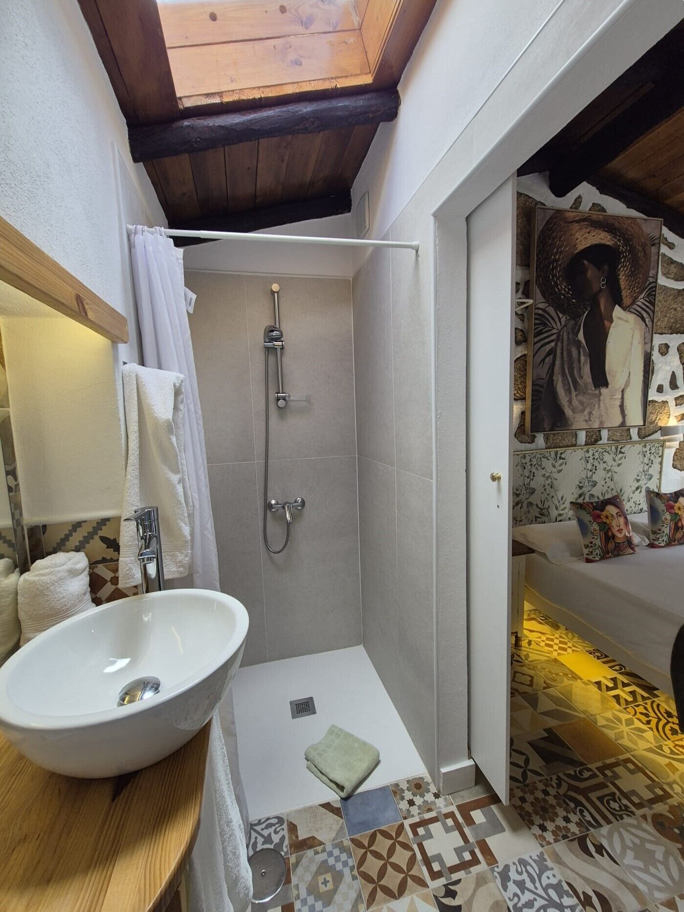 A bathroom with a large white sink, a shower with a glass door, and a tiled floor with a geometric pattern.