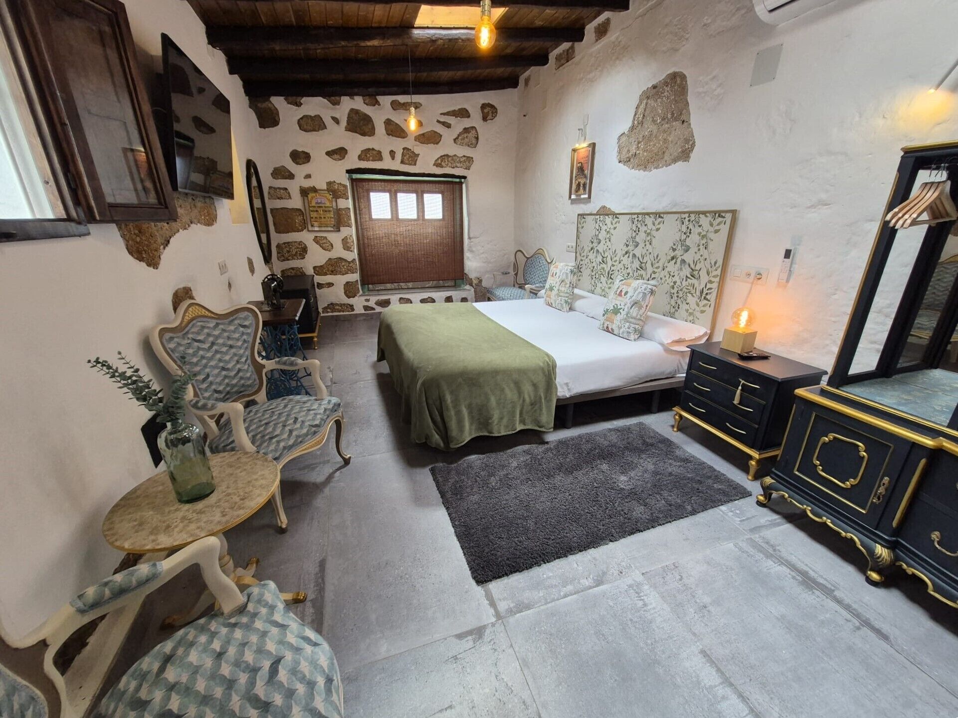 A cozy room with a bed, a small table, a chair, and a dresser.