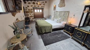 A cozy room with a bed, a small table, a chair, and a dresser.