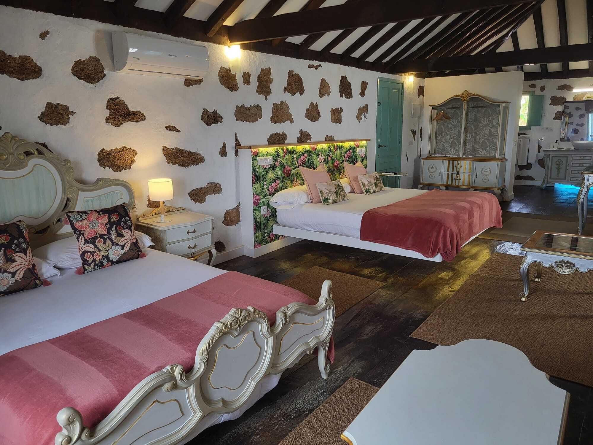 A bedroom with two beds, a nightstand, a dresser, and a mirror.