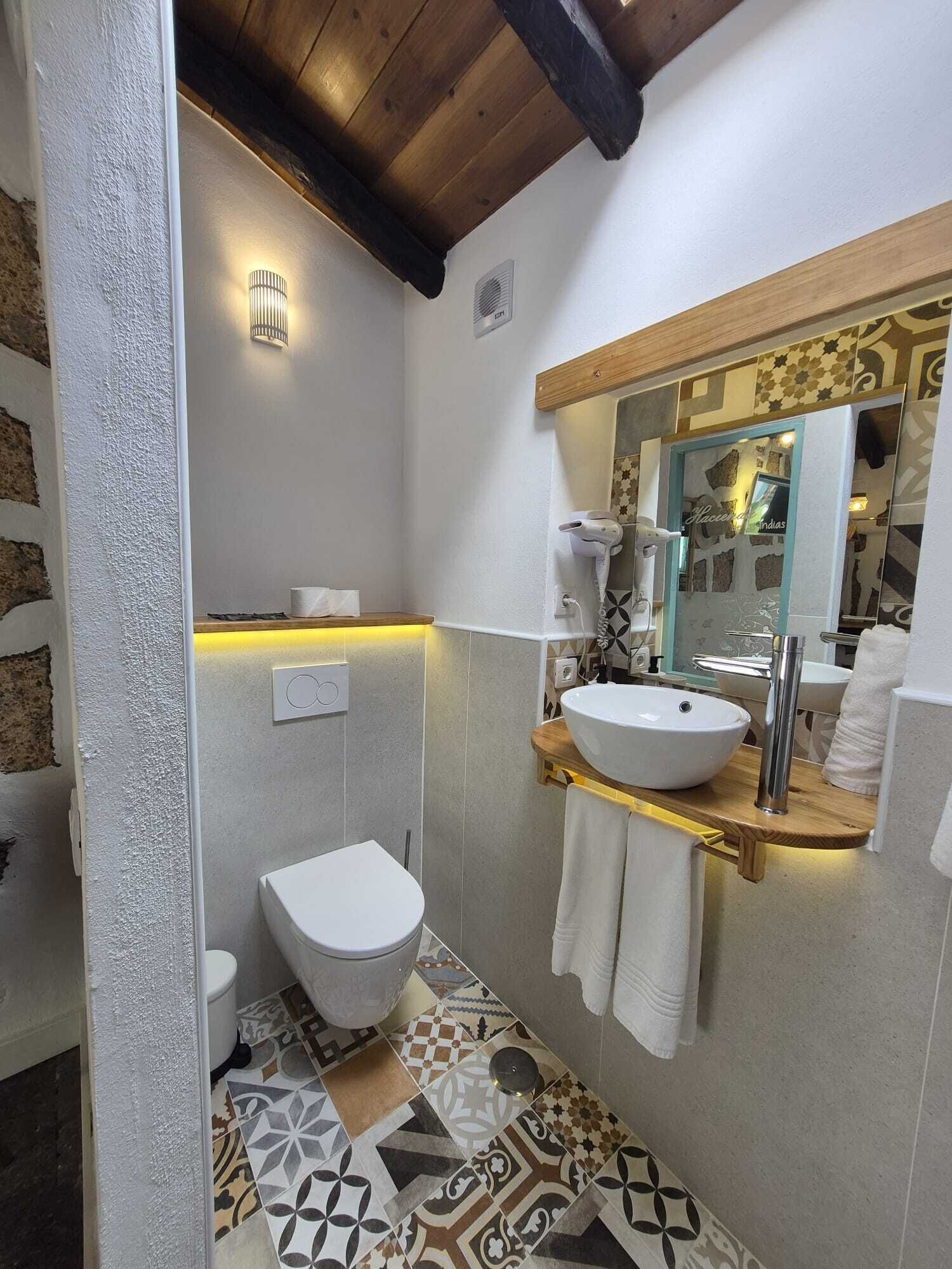 A bathroom with a white toilet, a vessel sink, and a mirror above the sink.