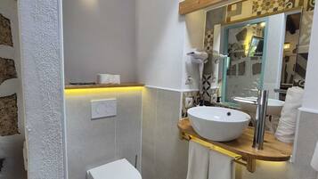 A bathroom with a white toilet, a vessel sink, and a mirror above the sink.