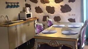 A dining area with a stone-patterned wall, a wooden countertop with a microwave, and a table set with plates and chairs.