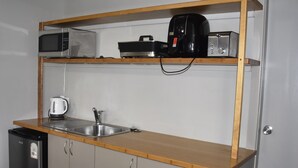 En kompakt tekøkken med mikroovn, kaffemaskine og en lille vask.
