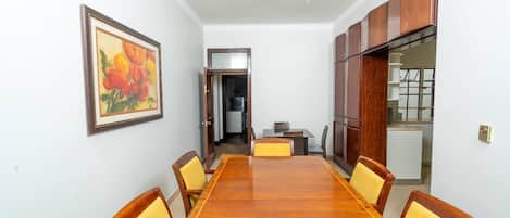 A conference room with a long wooden table, yellow cushioned chairs, a framed painting, and wooden cabinets.