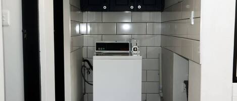 A compact kitchen with a white refrigerator, a microwave, and dark cabinets.