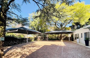 Un patio al aire libre con suelo de ladrillo, zonas de estar cubiertas y un edificio con ventanas.