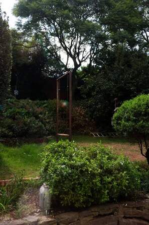 A garden with a swing set, a stone wall, and various plants.