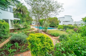 Una casa moderna con piscina, rodeada de exuberante vegetación y un jardín bien cuidado.