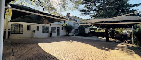 A courtyard with a paved floor, covered seating areas, and a building with windows and doors.