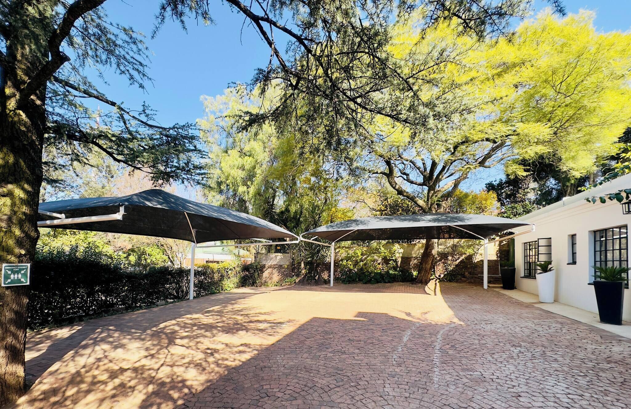 Un patio al aire libre con suelo de ladrillo, zonas de estar cubiertas y un edificio con ventanas.