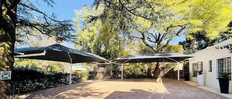 Un patio al aire libre con suelo de ladrillo, zonas de estar cubiertas y un edificio con ventanas.